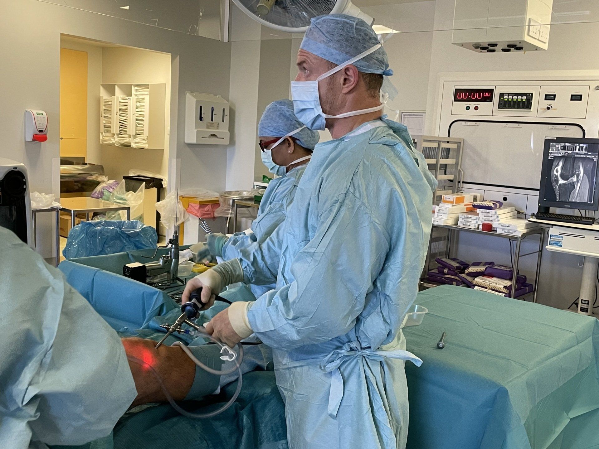 A group of knee surgeons are operating on a patient in an operating room.