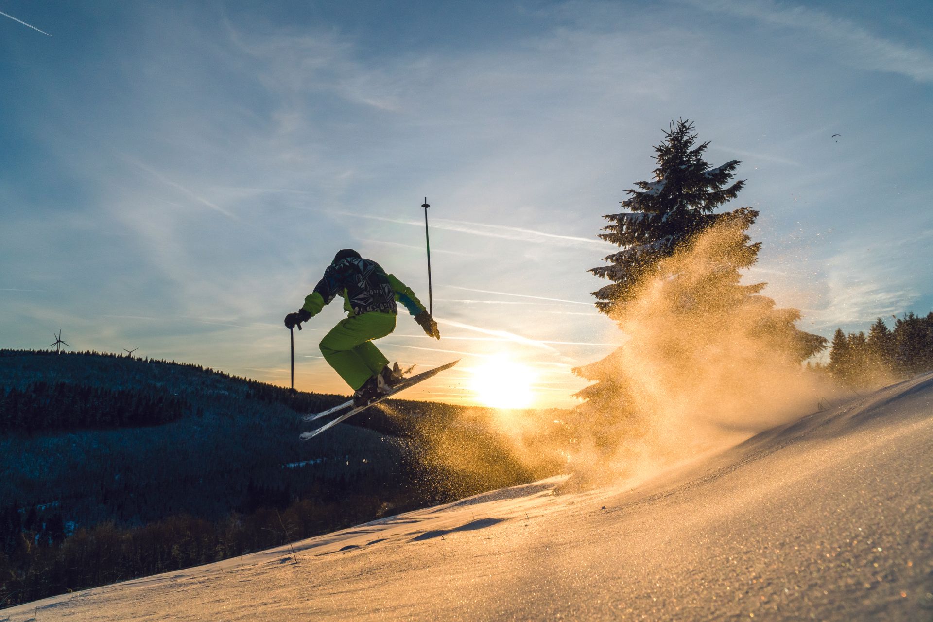 A person is skiing down a snow covered slope at sunset.