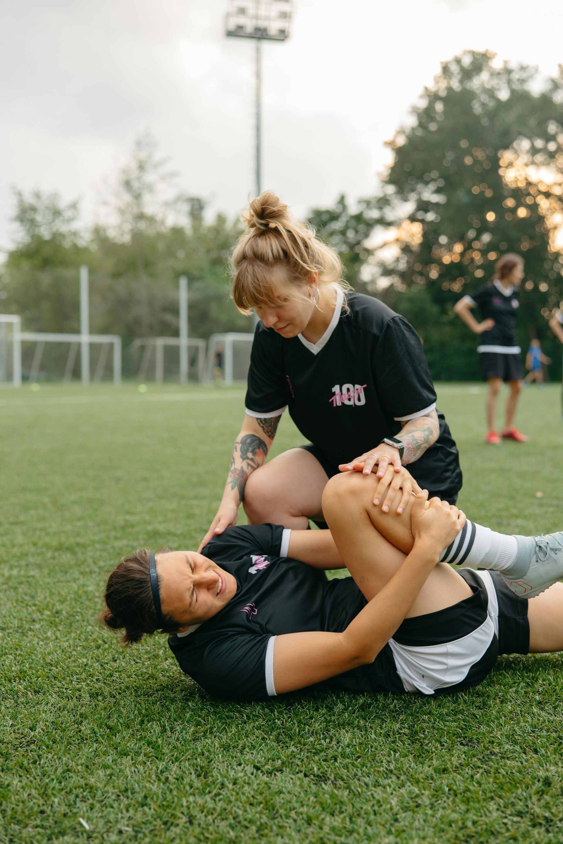 A woman holds her knee in pain on a rugby field