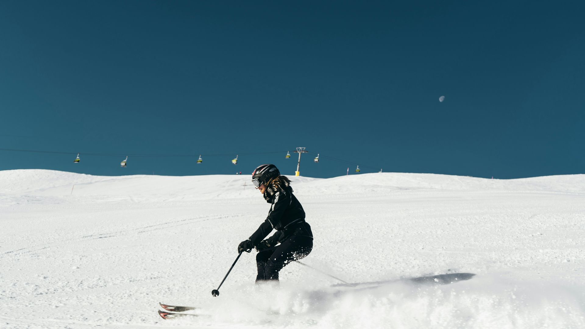 woman skiier on the slopes, kicking up a bit of snow