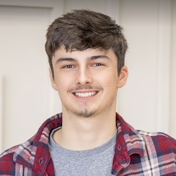 A young man in a plaid shirt is smiling for the camera.