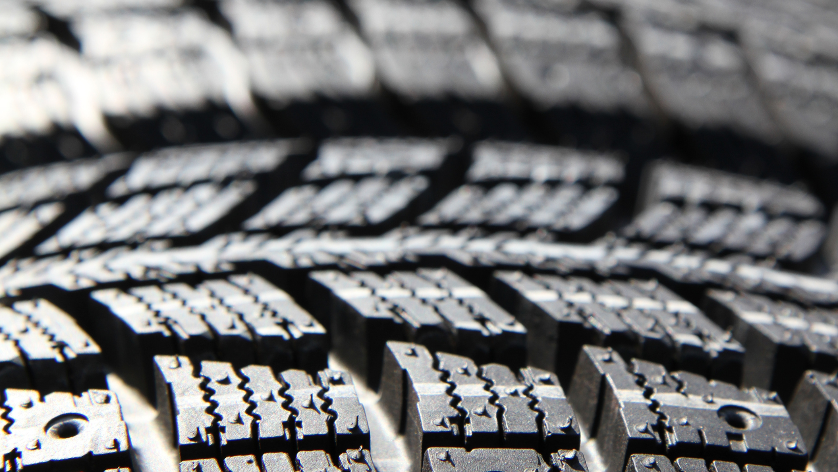 Close-up of a car tire tread with black rubber and wet, reflective texture