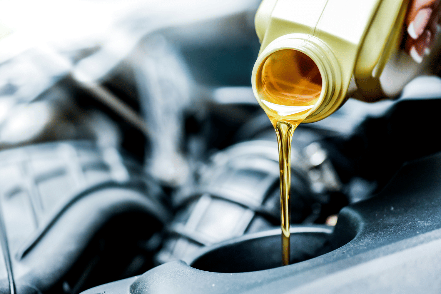 Motor oil pouring into an engine fill port from a white bottle