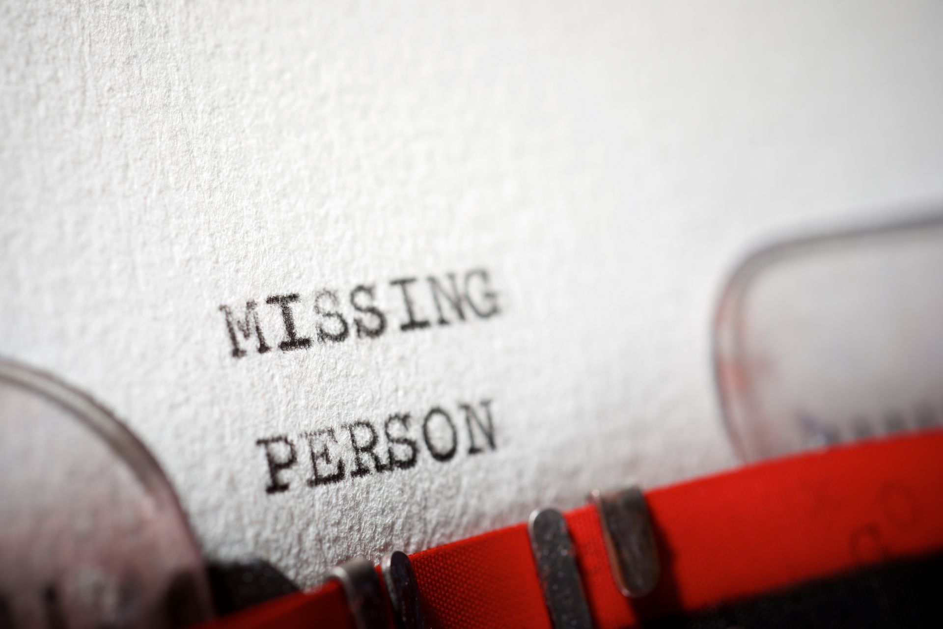 Close-up of a typewriter printing the words ‘Missing Person’ on textured white paper.