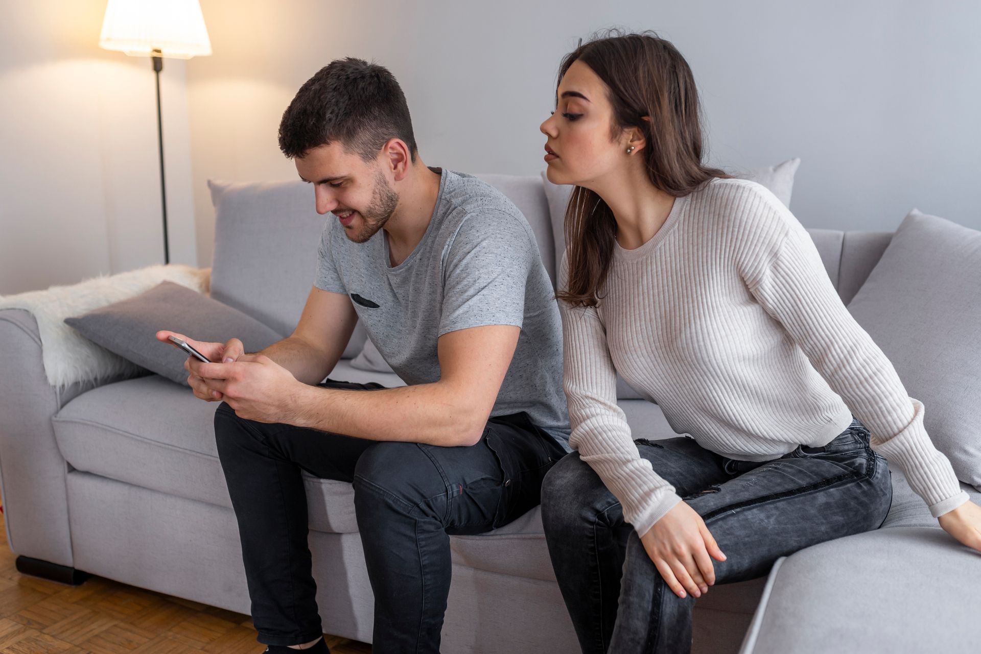 Couple sitting on couch and quarreling about smartphone. Couple sitting on couch and quarreling about smartphone.