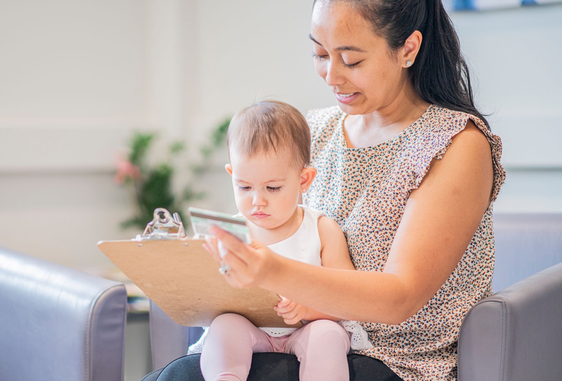 A Mom sits filling out forms with her infant daughter.