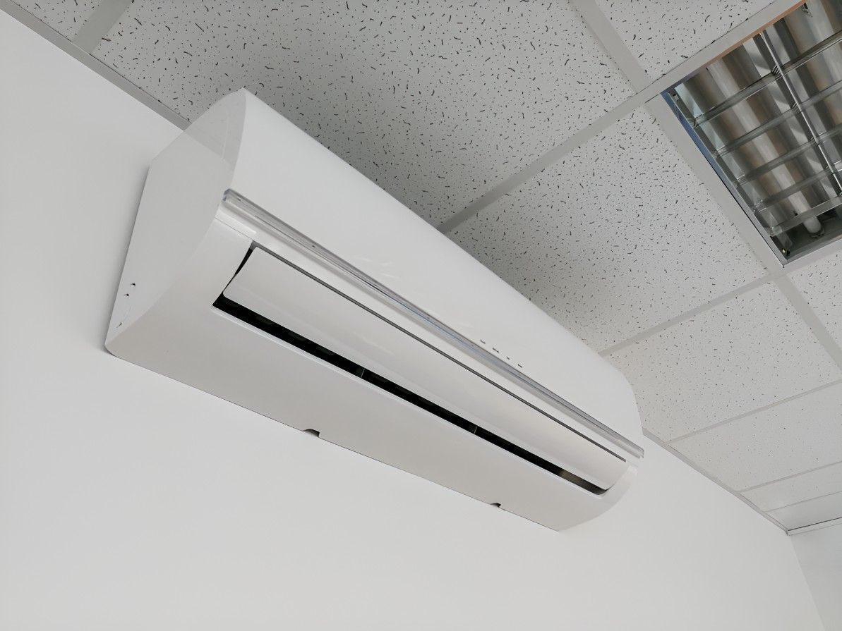 A White Air Conditioner is Mounted to a White Wall — Cooling Plus Refrigeration & Airconditioning in Ciccone, NT