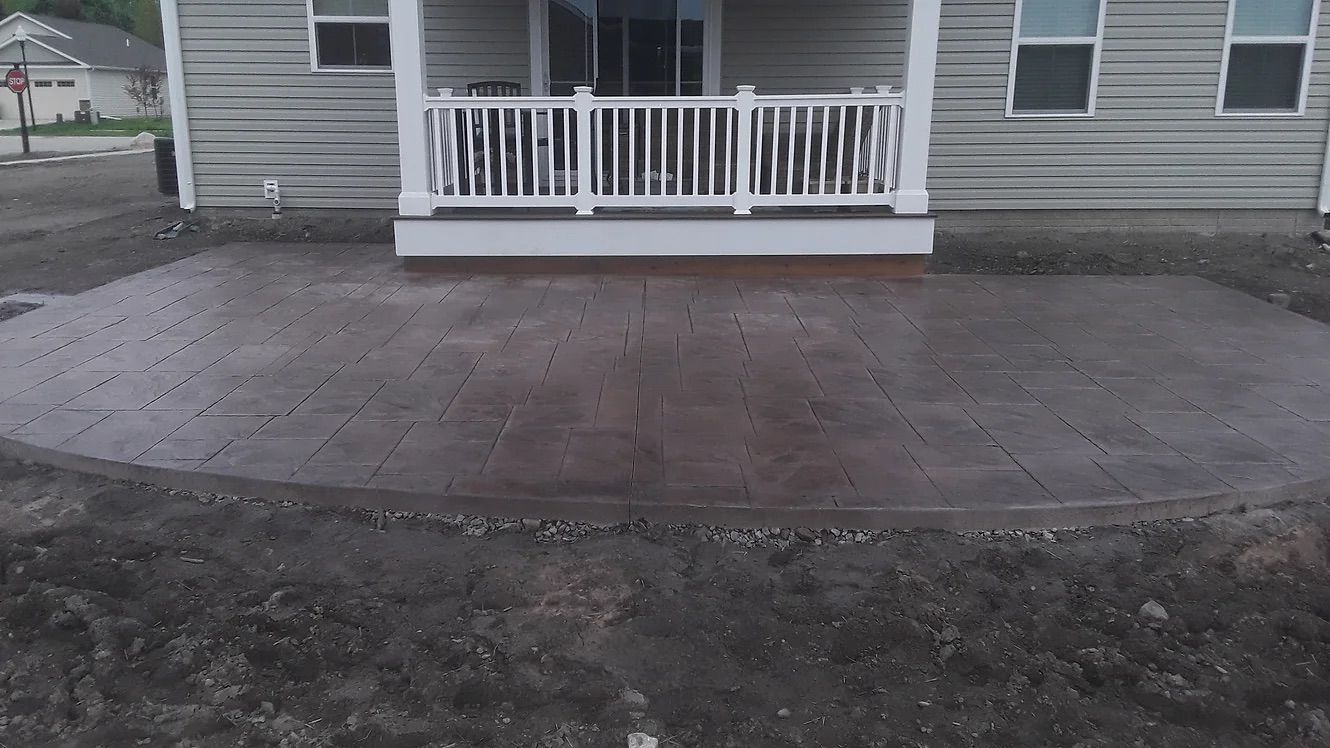 A house with a porch and a concrete patio in front of it.