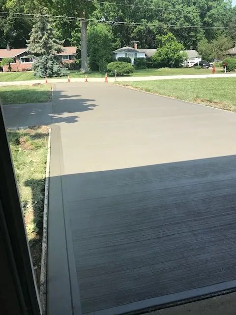 A view of a driveway from a window with houses in the background