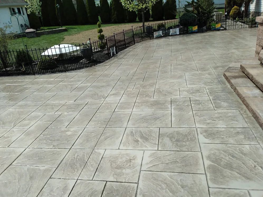 A concrete patio with a fence in the background