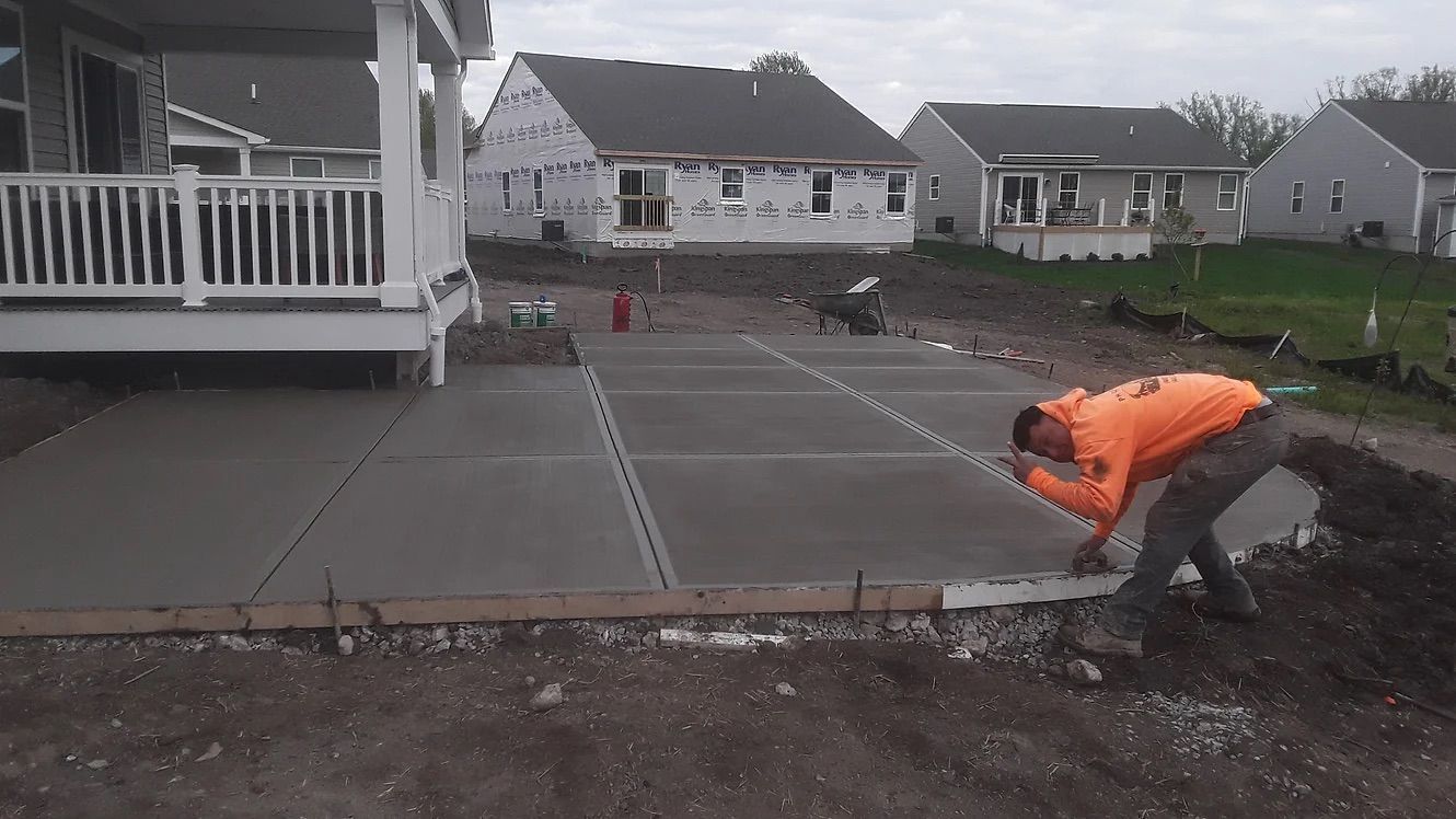 A man is working on a concrete driveway in front of a house.