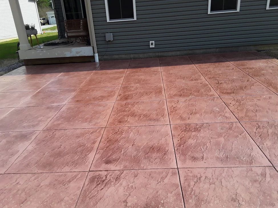 A red concrete driveway is in front of a house.