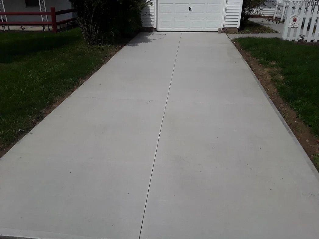 A concrete driveway leading to a white garage door.