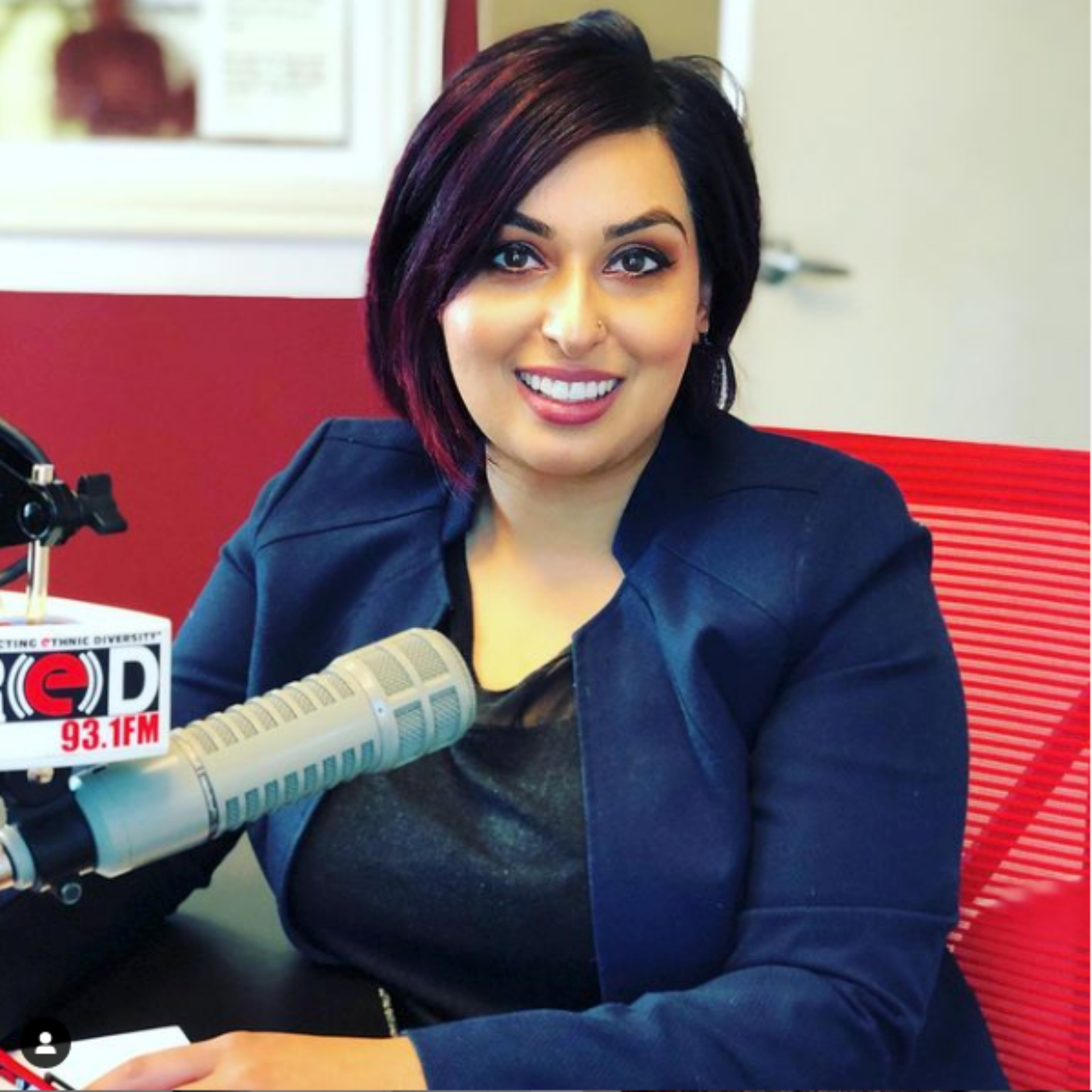 A woman sitting in front of a microphone that says 93.1 fm.
