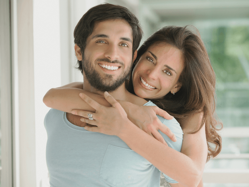 A man and a woman are hugging each other and smiling.