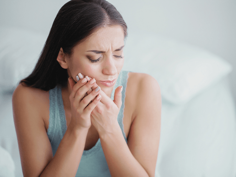 A woman is holding her mouth in pain because of a toothache.
