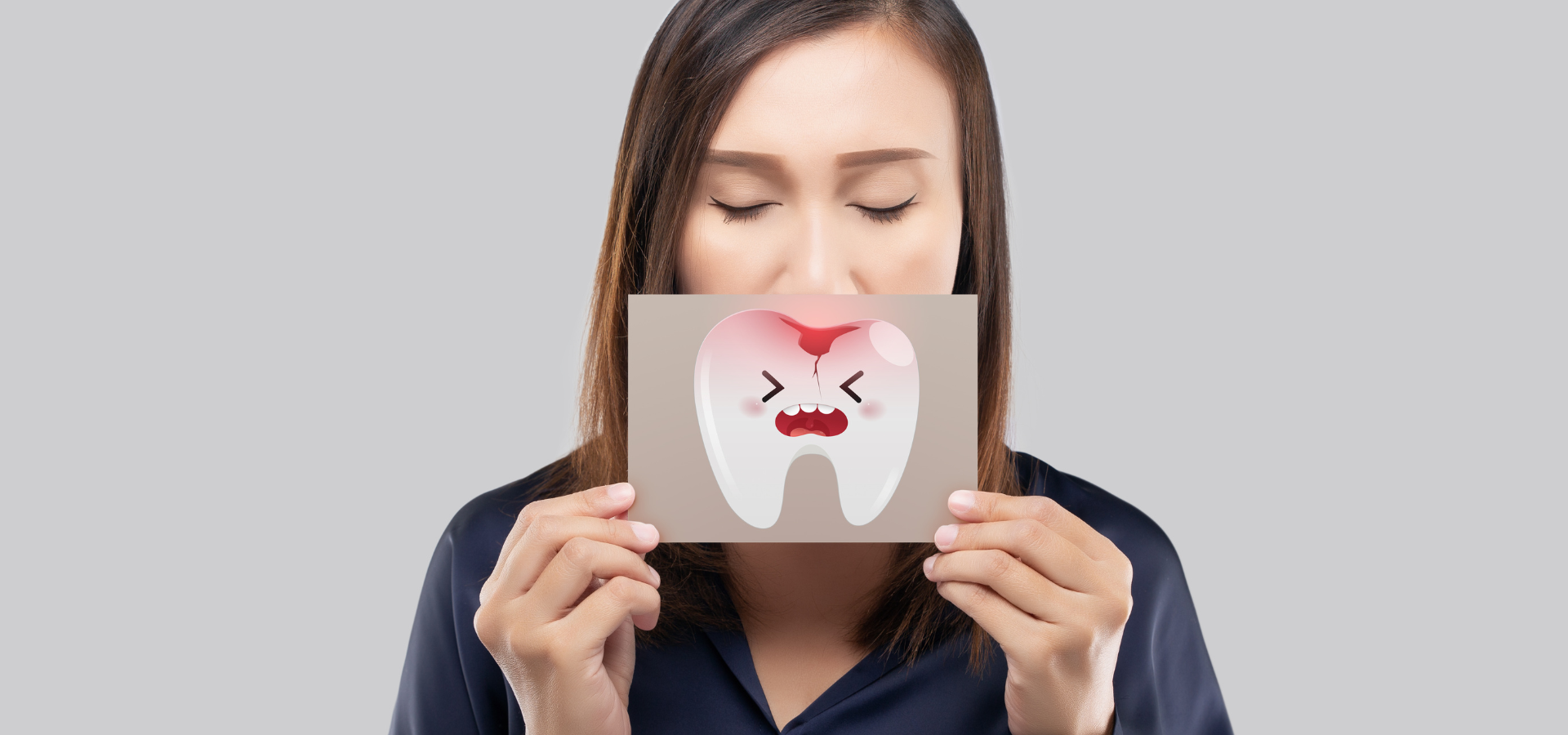 a woman is holding a card with a tooth on it in front of her face .