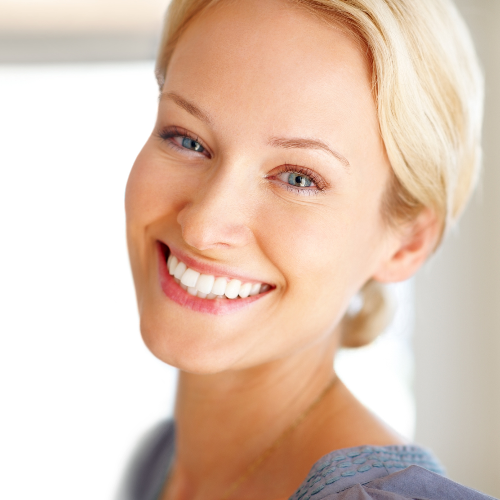 A woman with blonde hair and blue eyes is smiling for the camera.