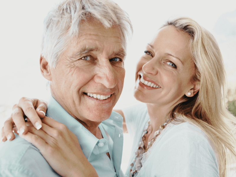 A woman is hugging an older man and they are smiling for the camera.