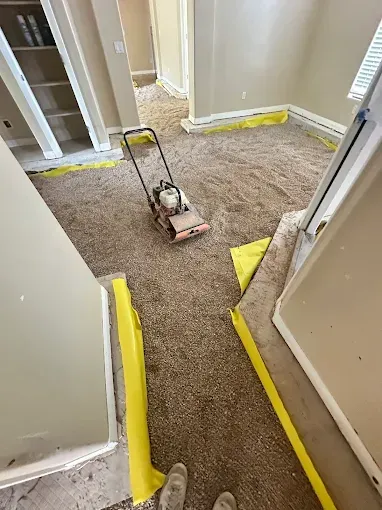 Carpeted room with a machine; yellow tape protects walls.