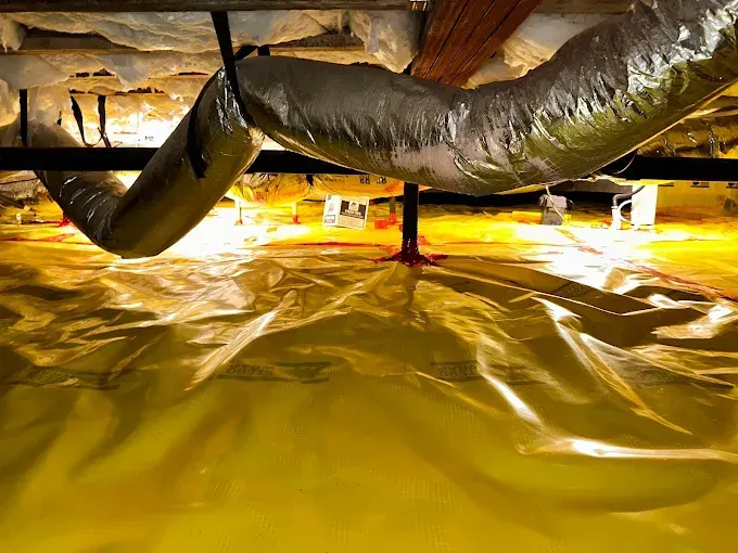 Crawlspace with yellow vapor barrier, ductwork, insulation, and support beams.