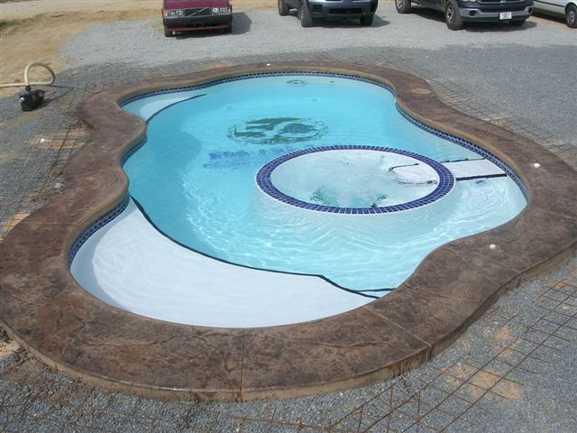 Small outdoor pool with blue water and a purple floating ring beside parked cars