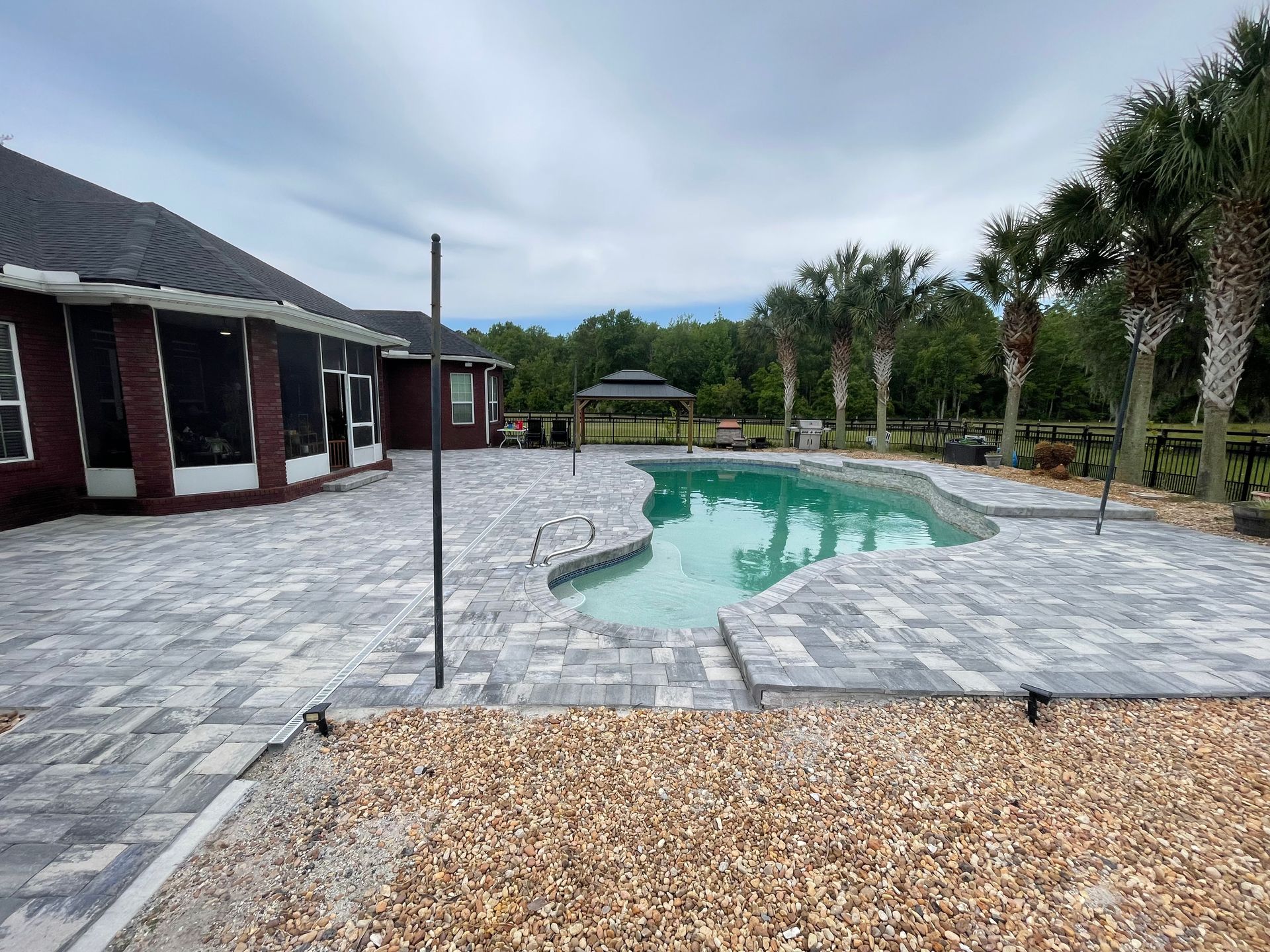 A large swimming pool is in the backyard of a house.