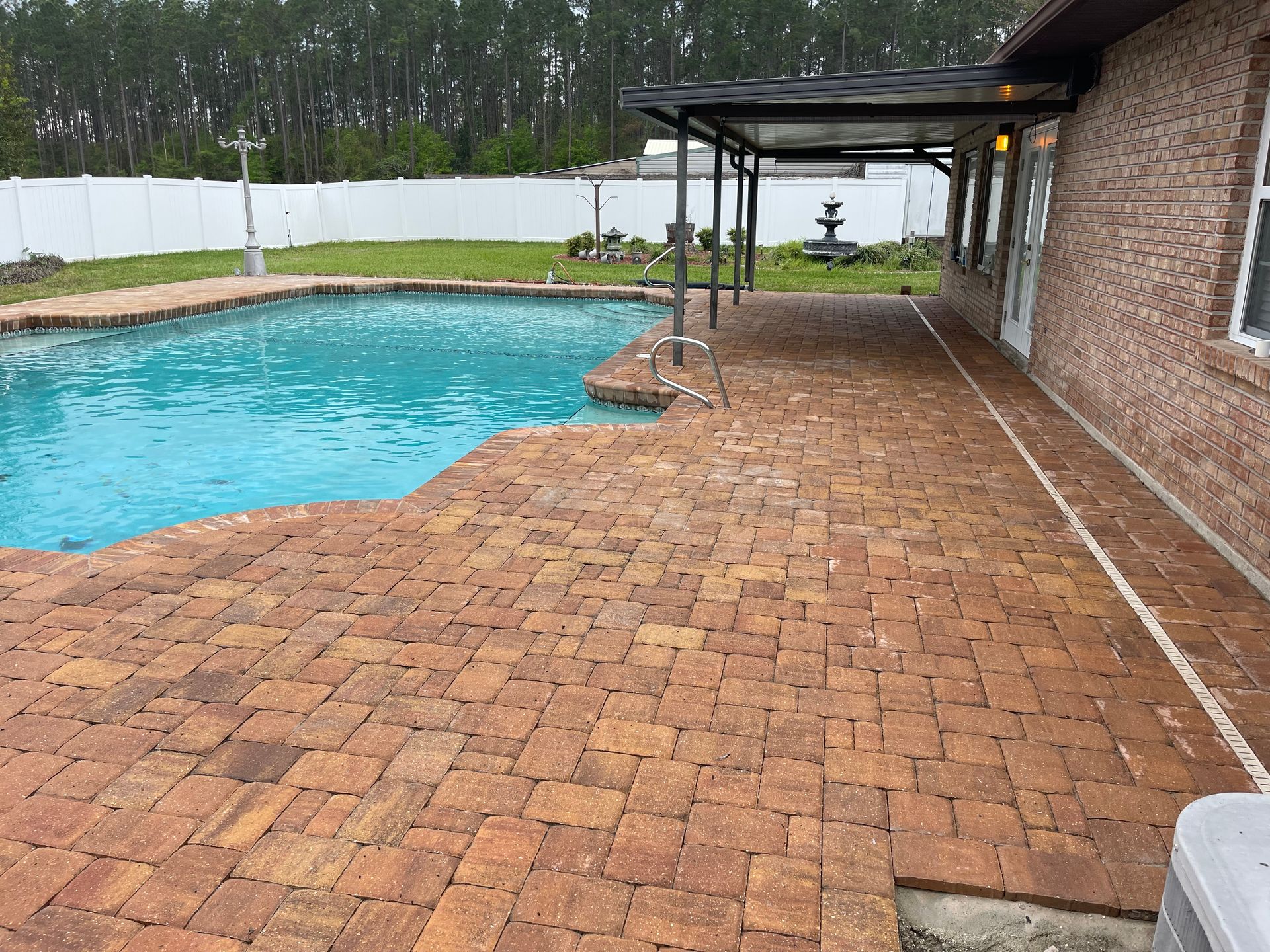 A brick patio with a swimming pool in the background.