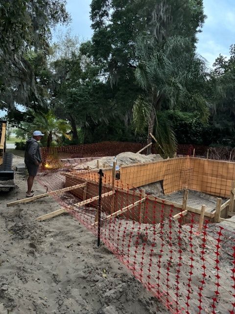 A man is standing in the dirt next to a construction site.
