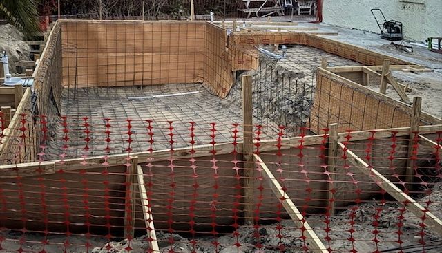 A swimming pool is being built in a backyard.