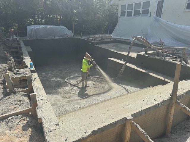 A man is spraying concrete into a swimming pool.