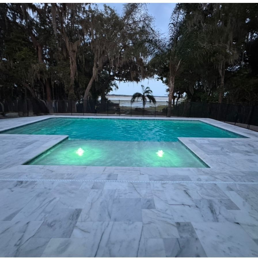 A large swimming pool is in the backyard of a house.