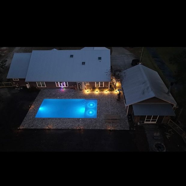 Pool enclosed in a white screened structure with blue water and light gray decking.