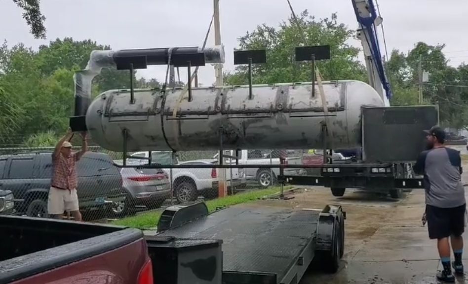 A man is carrying a large tank on a trailer.