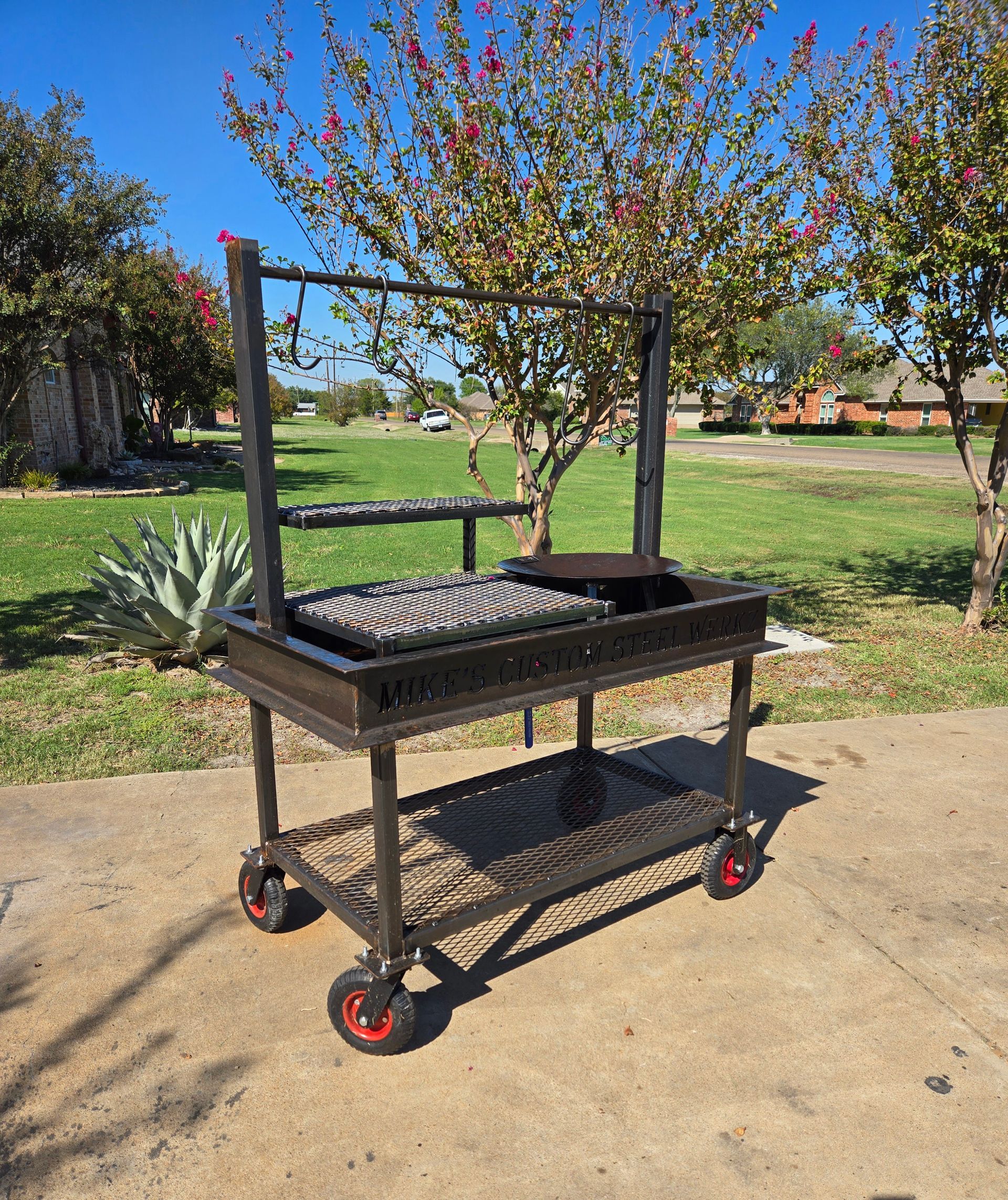 A large grill with wheels is sitting on the side of the road.