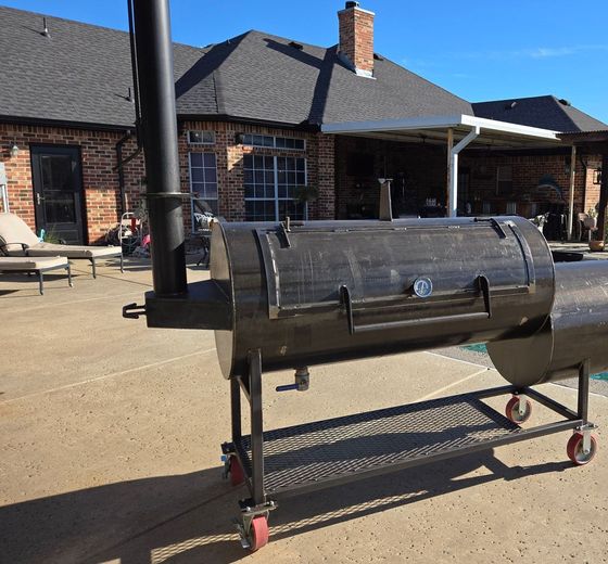 A large bbq grill is sitting in front of a brick house