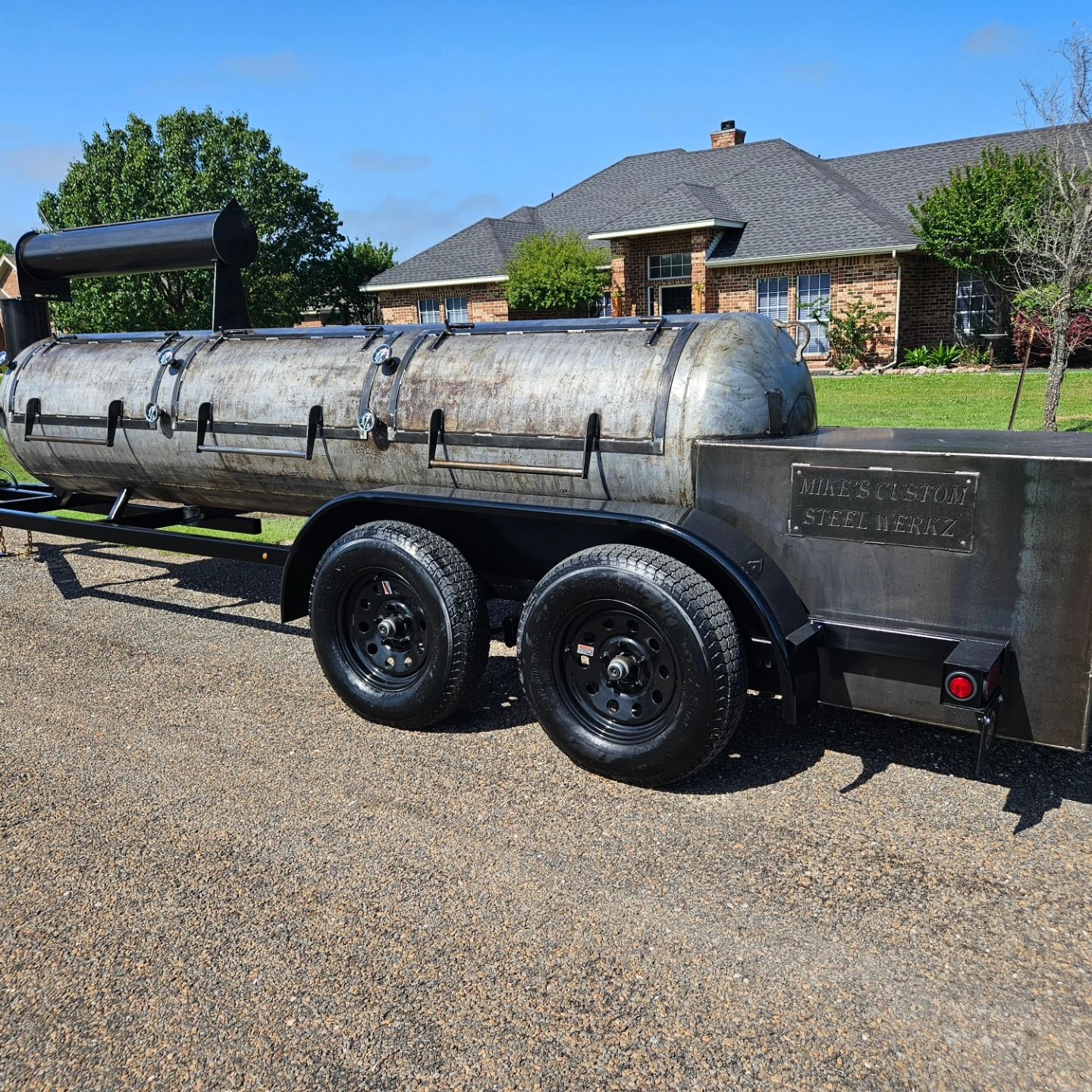 A trailer with a grill on it is parked in front of a house