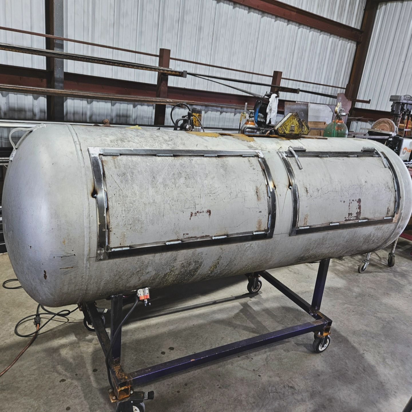 A large metal tank is sitting on a cart in a warehouse