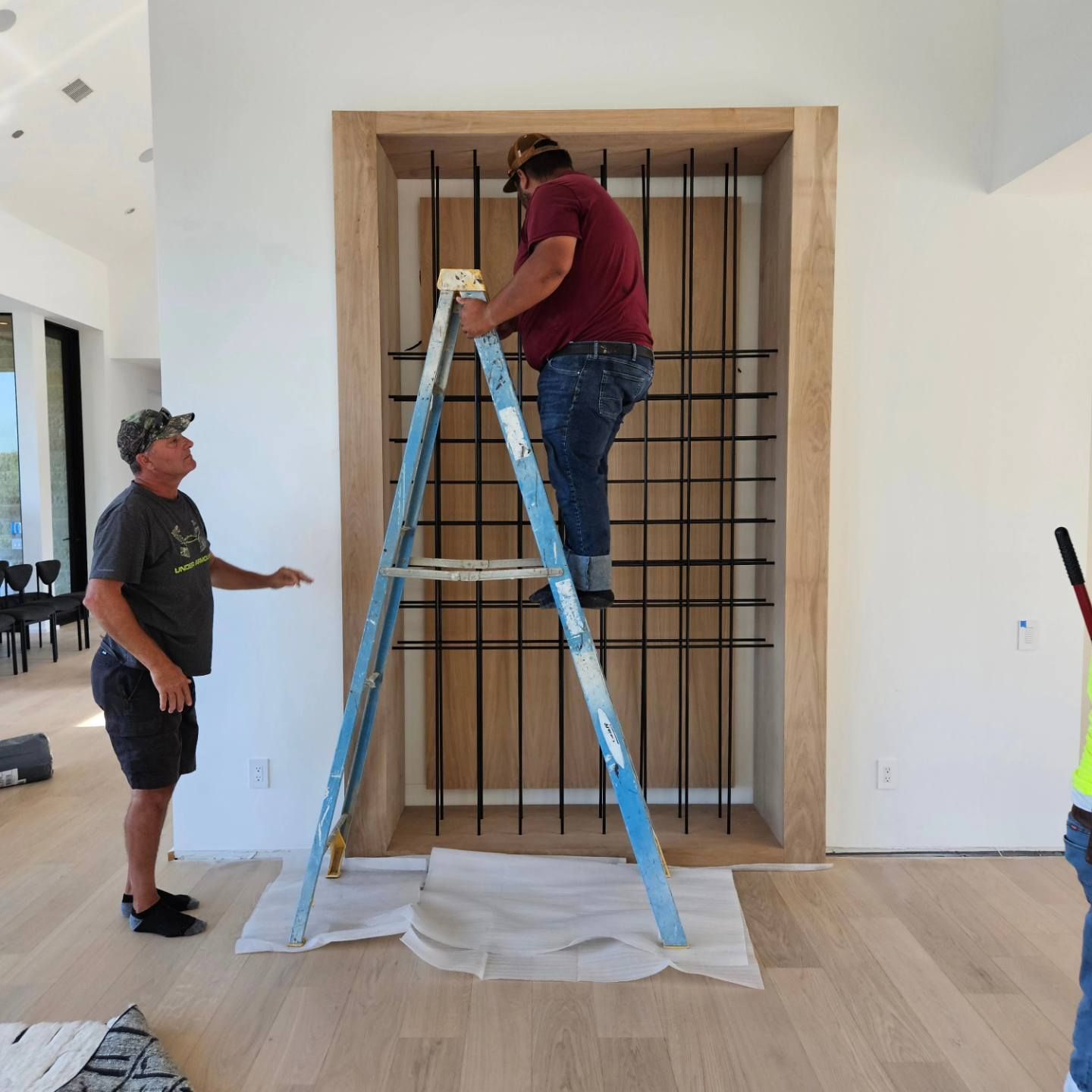A man standing next to a ladder with a man on it
