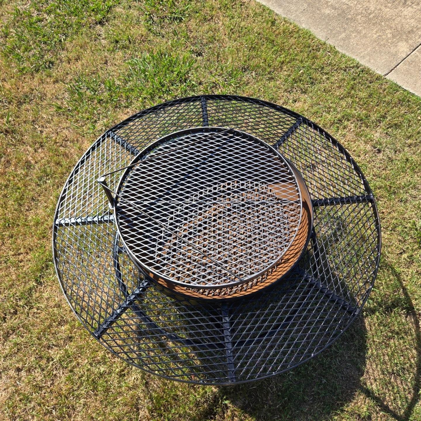 A fire pit is sitting on top of a lush green lawn.