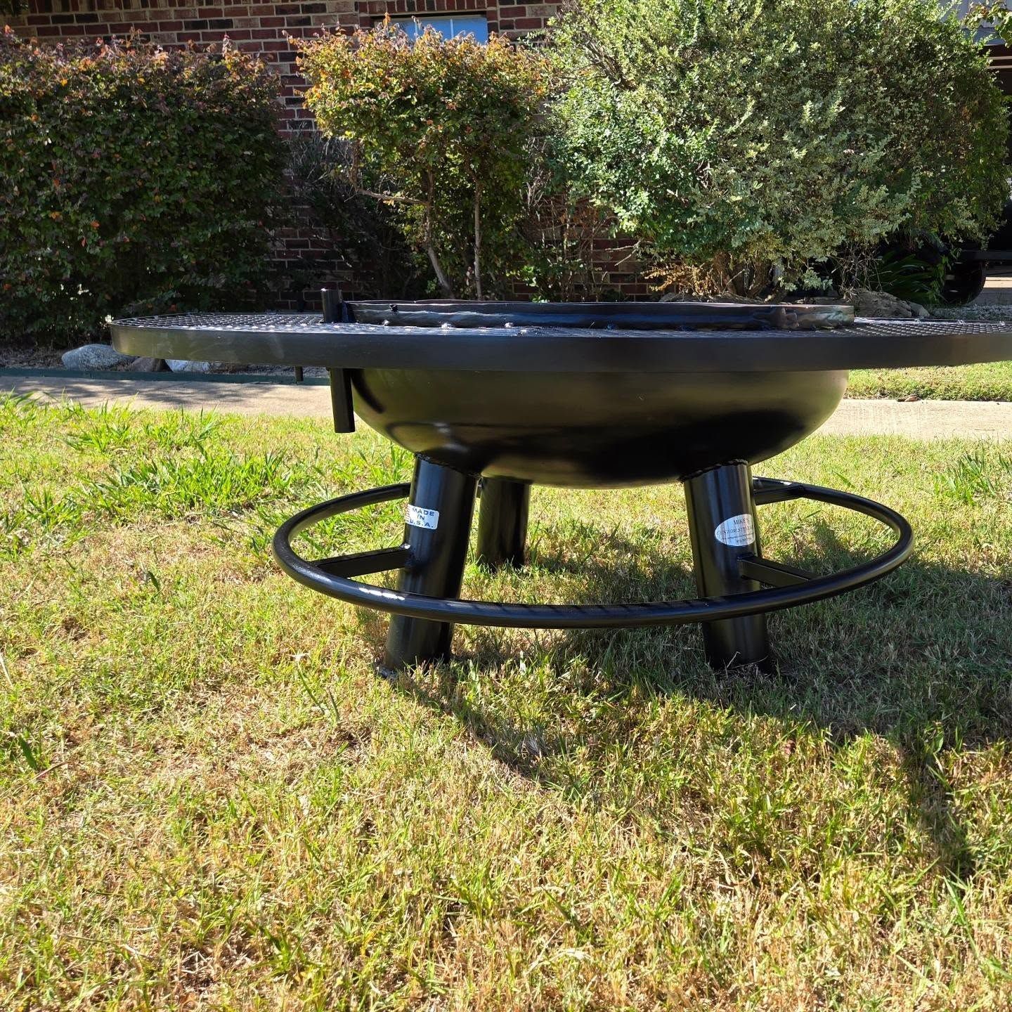 A fire pit is sitting in the middle of a lush green field.