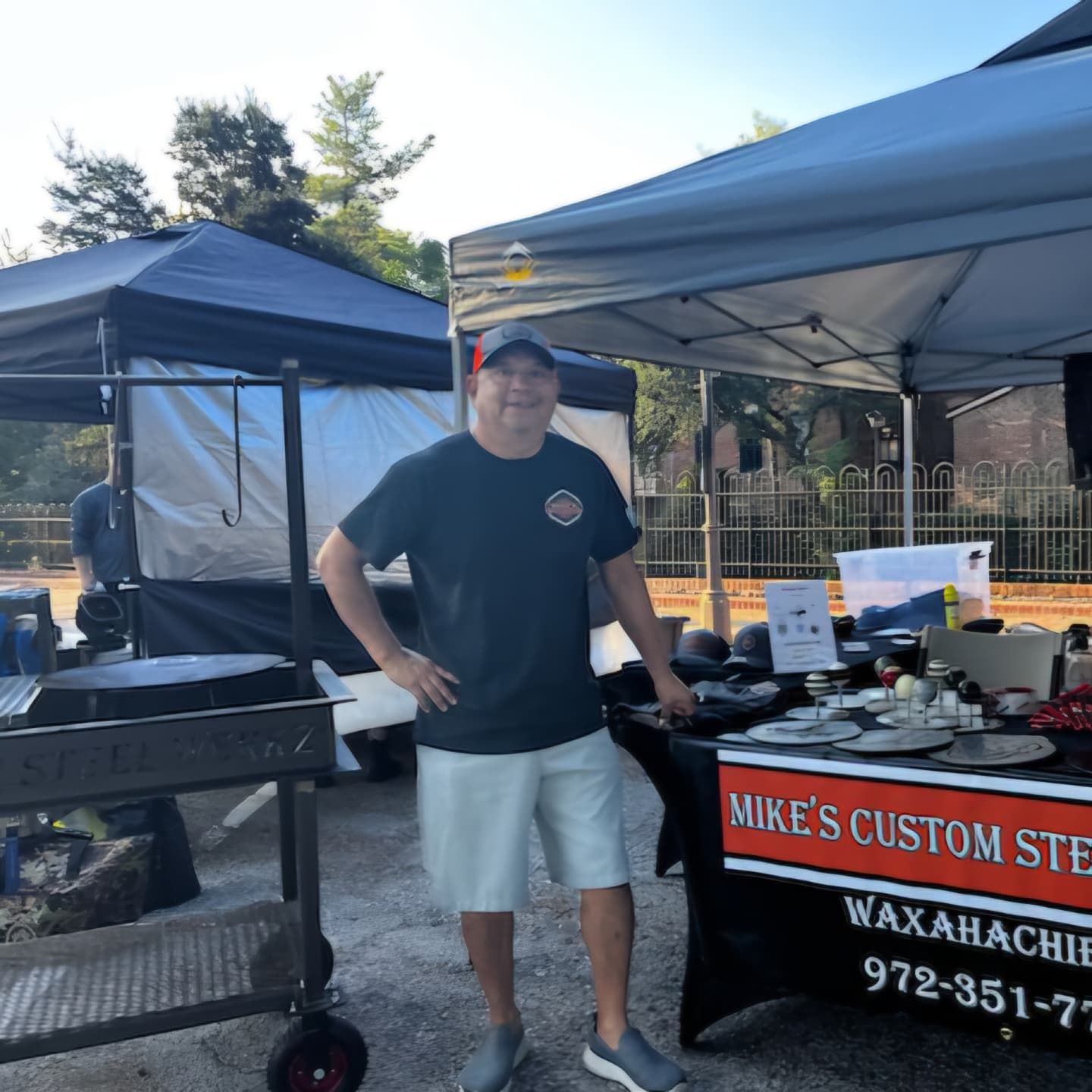 A man standing in front of a table that says mike 's custom smoke