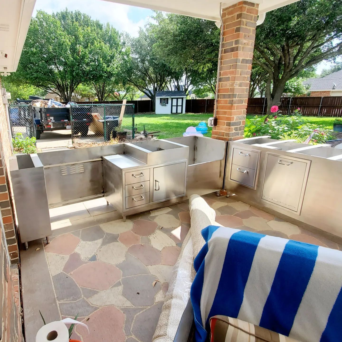 A patio with stainless steel cabinets and a blue and white striped blanket