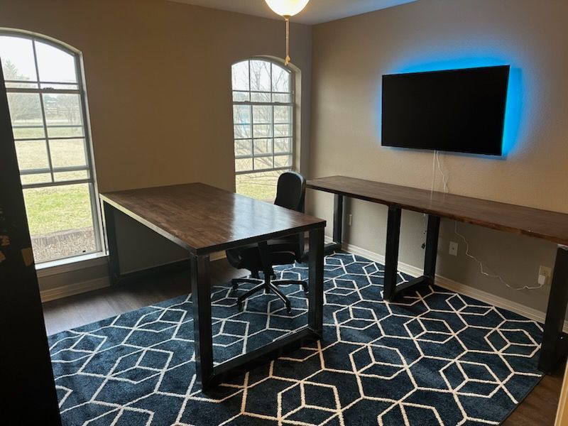A room with a desk and a television on the wall.