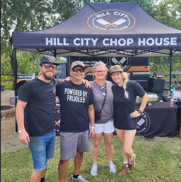 A group of people standing in front of a hill city chop house tent