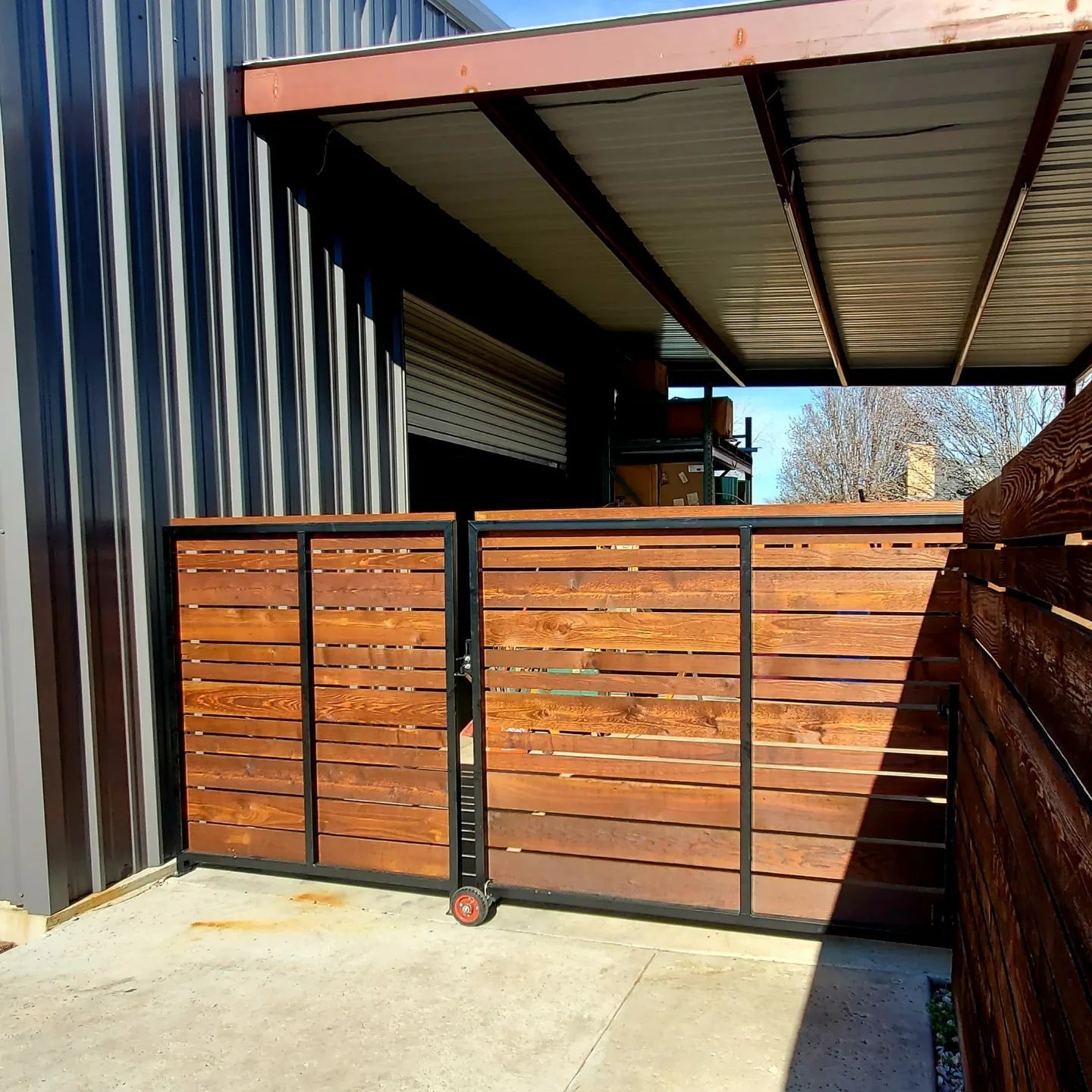 A wooden fence with wheels is in front of a building