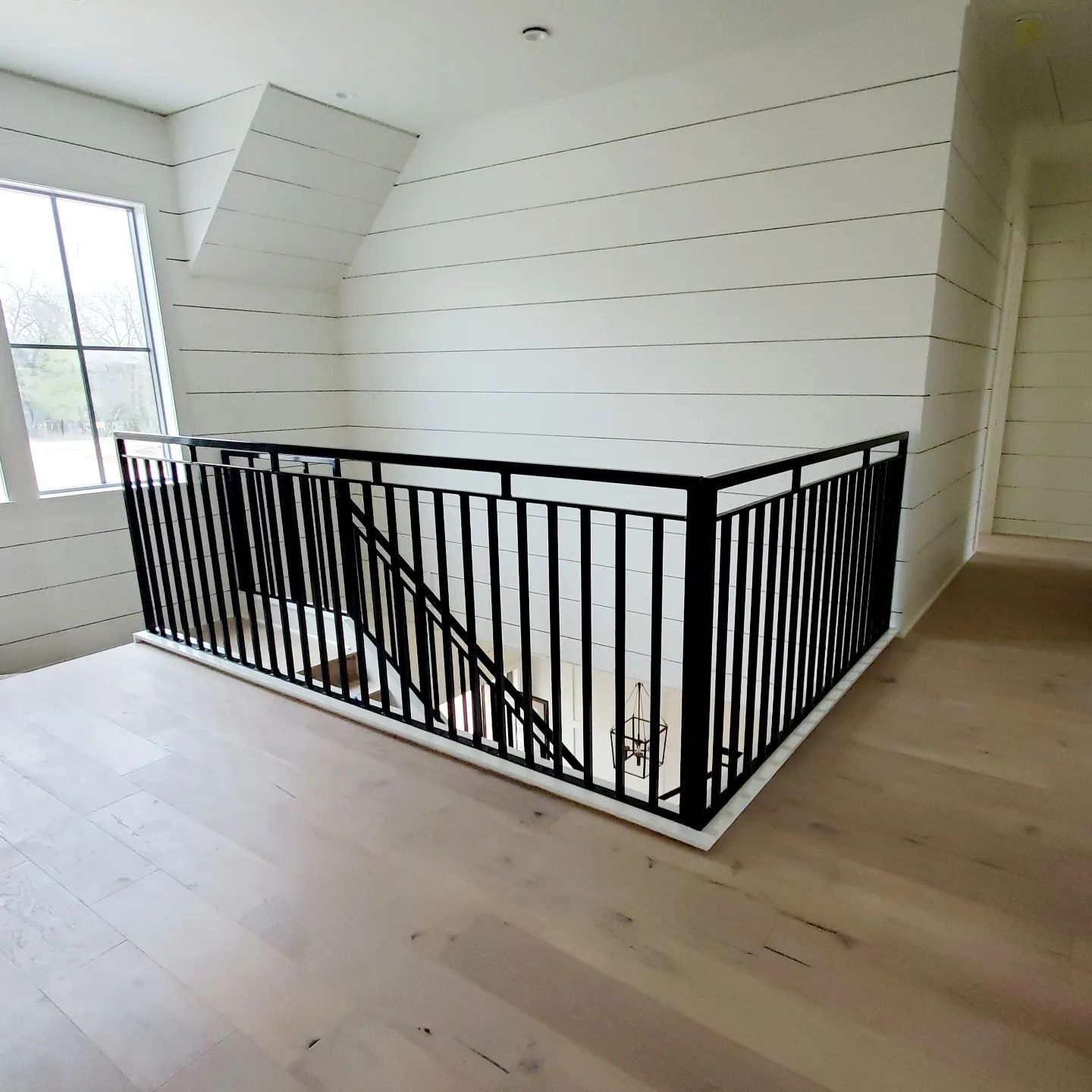 There is a staircase with a black railing in the middle of the room.