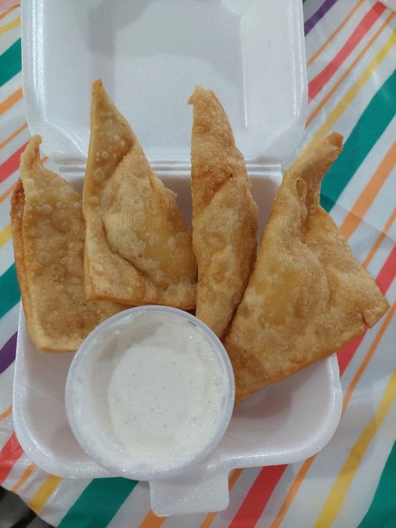 A styrofoam container filled with fried food and a dipping sauce.