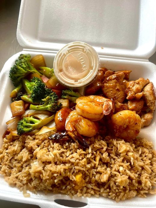 A styrofoam container filled with rice , shrimp , broccoli and chicken.