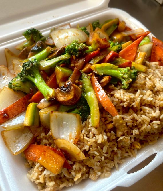 A styrofoam container filled with rice and vegetables.